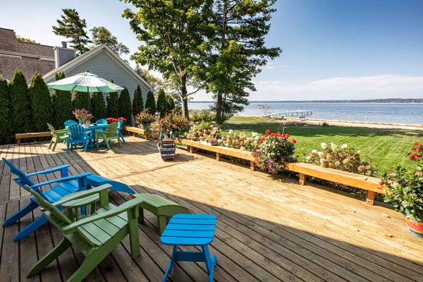 Waterfront deck with Adirondack chairs overlooking Grand Traverse Bay on a sunny summer day